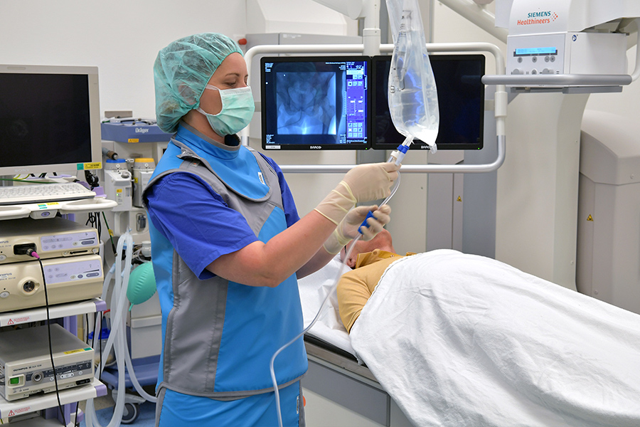 OP-Vorbereitung im MVZ Ärztin mit Monitor und Infusion bei OP-Vorbereitung